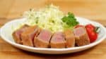 Placez le Gyukatsu sur une assiette avec les légumes d'accompagnement. Aujourd'hui, nous avons du chou blanc râpé, des pousses de brocoli, des tomates cerise, et du persil. 