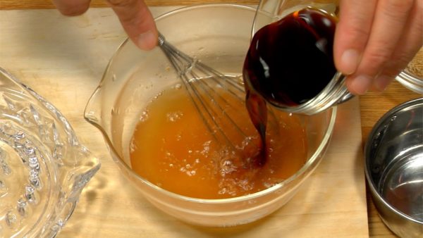 Let's make lemon soy sauce. Put the chicken stock powder in a bowl and dissolve in hot water. Add the sugar and stir until dissolved. Then add the soy sauce and vinegar to the mixture.