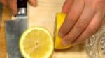 レモンは果汁がたくさん取れるように、まな板の上で押さえながら転がします。半分に切り、レモン絞り器で絞ります。