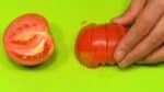 Vamos cortar os demais ingredientes. Corte o tomate ao meio, remova o cabinho do tomate e corte-o em 6 pedaços no formato de cunha. Então corte as fatias de presunto em finas tiras.