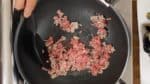 Vamos fazer o Mabo Nasu. Em uma panela, esquente o óleo vegetal. Então, adicione a carne suína moída e frite em fogo médio. Separe-a em pedaços pequenos.