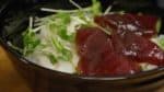 Add the kaiware radish sprouts or garden cress. Then, arrange the marinated maguro slices on top.