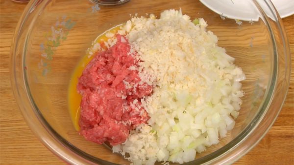 Để hành vào bát. Thêm trứng đã đánh, vụn bánh mì mềm, tương cà chua (ketchup) và sốt Worcestershire kiểu Nhật vào thịt.