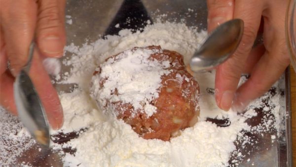 Let’s bread the meat mixture. With a pair of spoons, place the meat ball onto a thick layer of cake flour.