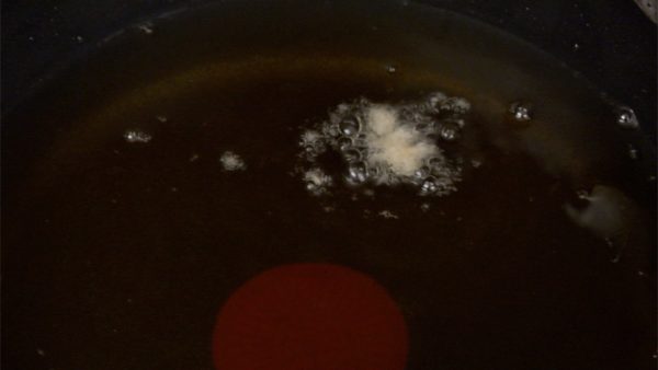 油で揚げましょう。菜箸で混ぜて温度を均一にします。油の温度は約170℃です。パン粉を落として温度をチェックします。ご覧のように小さい泡が出ていたら適温です。