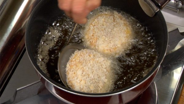 With a mesh strainer, gently place the menchi-katsu into the oil.