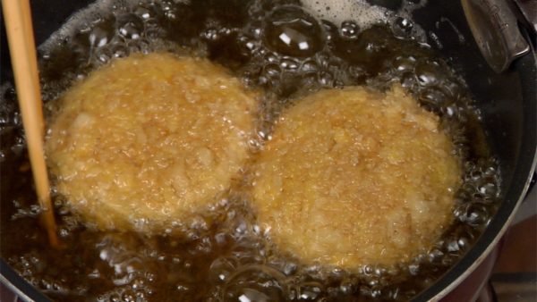 When the outer layer firms up, gently rotate them with the chopsticks to brown evenly. Keep ladling the oil and then gently flip the menchi-katsu.