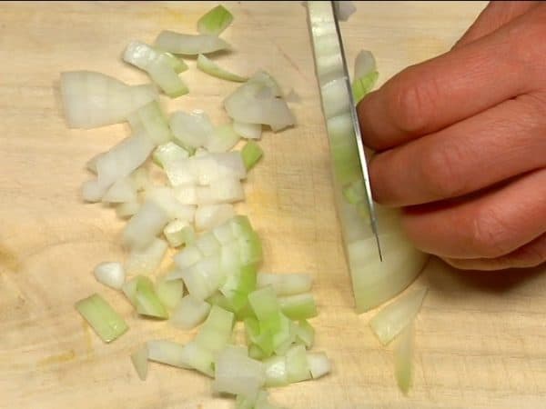 Die Zwiebel fein hacken. Dazu zuerst senkrecht mehrfach einschneiden, dann die Zwiebel drehen und quer zu den ersten Schnitten in gleich große Stücke schneiden. Die Stiele der Champignons entfernen und sie in 1/2 cm dicke Scheiben schneiden.