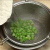 Place the frozen green peas into a mesh strainer. Briefly rinse under hot water, removing the freezer smells. Strain and salt the peas.