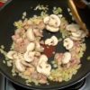 When the chicken begins to brown, add the button mushrooms. Continue to stir and distribute the oil evenly. Add the white wine and allow the alcohol to evaporate completely.
