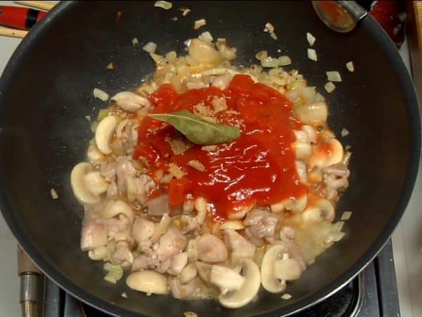 ここにトマトの水煮、トマトケチャップ、砕いた固形コンソメ、ローリエを加えます。均一に混ぜてしばらく煮ます。ソースを焦がさないように気を付けてください。