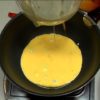Let's make Omurice. Add the olive oil to the heated pan and swirl to coat. Test the surface of the pan with a tiny bit of egg and pour the egg mixture on at once.