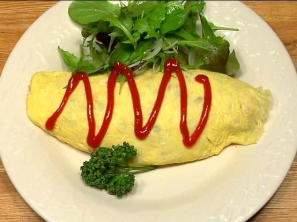 Shape the omurice with a paper towel. Place the baby salad greens and parsley leaves next to the omurice. Finally, garnish with the tomato ketchup.