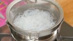 しらたきのアク抜きをします。洗ったしらたきはハサミで食べやすい長さに切ります。熱湯の入った鍋に入れます。沸騰させた後、30秒ほど茹でます。