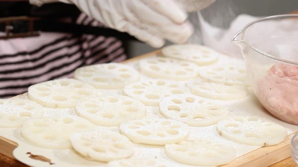 Line up the lotus root onto a cutting board, making 8 pairs of slices. Remove the excess moisture with a paper towel. Then, sprinkle on the cake flour.