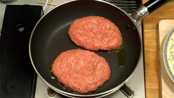 Let's fry the hamburg steak. Heat olive oil in a pan. Lightly press on the meat and make a dent in the center. This will reduce the cooking time.