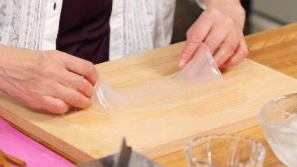 Hold the middle of both edges, gently lift and place it onto a cutting board.
