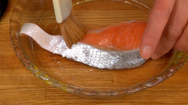 Vamos preparar o filé de salmão salteado. Remova o excesso de umidade com uma toalha de papel. Coloque o saquê em ambos os lados para diminuir o cheiro do peixe. Recomendamos fazer esse processo o mais rápido possível após a compra do salmão.