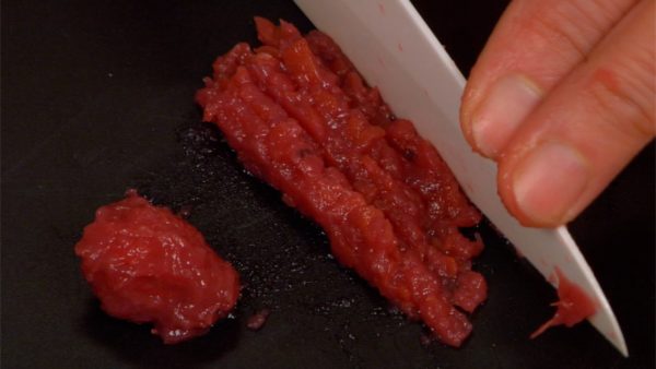 Remove the stone of the umeboshi, pickled Japanese plum. Chop up the umeboshi flesh with a knife, making umeboshi paste.