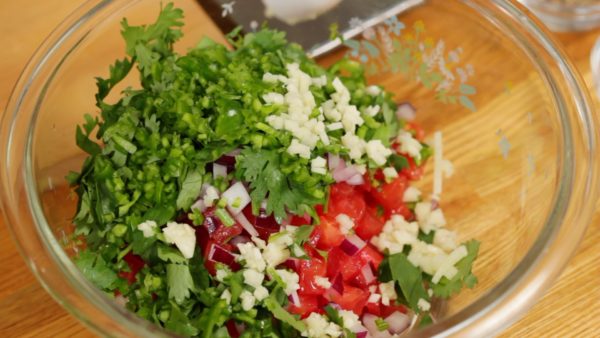 Combine the diced tomatoes, chopped red onion, coriander leaves, green bell pepper, chopped garlic clove and green chili pepper. Lightly toss to coat.