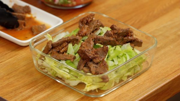 Préparez la Salade Taco. Placez une quantité généreuse de feuilles de laitue en lamelles dans un plat (idéalement carré). Placez la viande à taco dans les coins. 