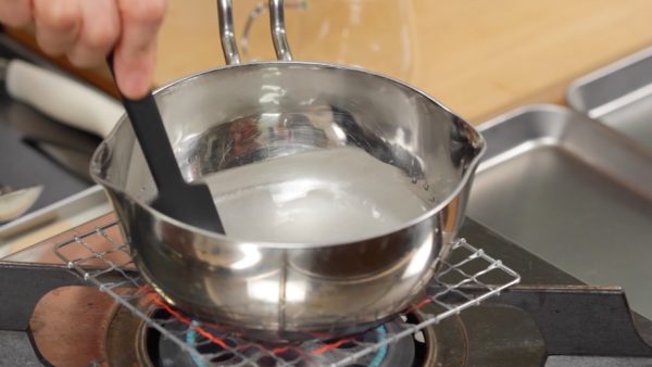 Hagamos el sirope. Combina el agua y el azúcar en una olla. Enciende el fuego y disuelve el azúcar. Cuando comience a hervir, baje el fuego a bajo. Reduce el sirope de 2 a 3 minutos.