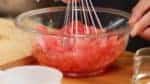 Place the watermelon into a bowl. Add about half of the syrup. And crush the flesh with a balloon whisk.