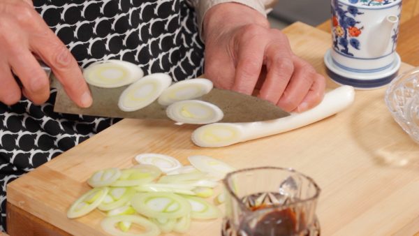 Slice the long green onion into thin slices using diagonal cuts.