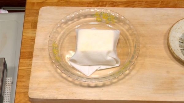 豆腐は厚手のキッチンペーパーでくるみます。冷蔵庫でしばらく置き、軽く水気を取ります。
