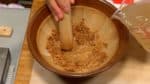 Ajoutez petit à petit le bouillon dashi froid dans le miso et dissolvez-le avec le pilon surikogi. Ensuite, ajoutez les glaçons. 