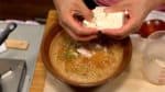 Ajoutez le chinchard japonais. Retirez l'essuie-tout, séparez le tofu à la main en bouchées et plongez-les dans le bouillon dashi. Séparer le tofu à la main va l'aider à absorber le bouillon. 