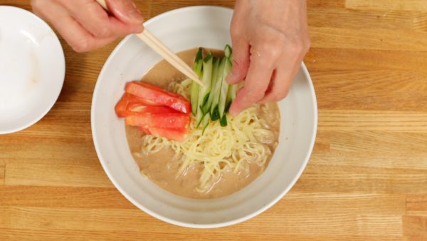 Place the noodles into the bowl. Arrange the tomato cut into sticks, thickly shredded cucumber, meat mixture and chopped spring onion leaves.