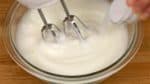 Let’s make the batter for the roll cake. Using a hand mixer, beat 4 egg whites in a bowl. When the white is foamy as shown, add half of the sugar. Beat it again and then add the rest of the sugar.