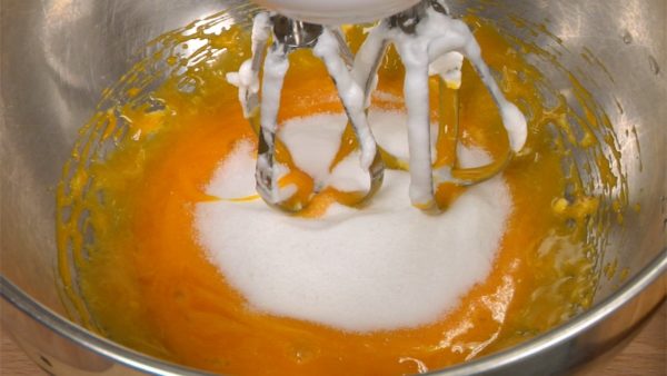 Remove the meringue from the beaters. Then, lightly beat the 4 egg yolks in a bowl. Add the sugar and continue to mix.