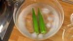 Retira y enfría rápidamente la okra en un recipiente con agua helada para ayudar a retener su color. Cuando se enfríe, retira el exceso de agua con una toalla de papel. Pícala en rodajas finas.