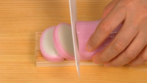 Remove the stems of the cherry tomatoes and cut each into 4 wedges. Cut two slices from the kamaboko fish cake and remove them from the wooden base. Cut them in half, making quarter moons.