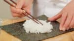 Préparez l'onigirazu. Placez une feuille d'algue nori grillée sur un film plastique et saupoudrez de sel. Ensuite, placez la moitié du riz sur le nori et étalez-le. Utilisez du riz cuit chaud pour que vous puissiez facilement le former. 