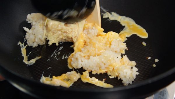 Den Reis rasch gleichmäßig mit dem Ei bedecken und die Masse mit der Rückseite des Schöpfers zerteilen. Auf hoher Stufe braten und hierbei jedes Reiskorn voneinander trennen, um alles aufzulockern. 