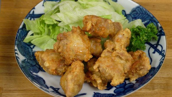 Place the karaage next to the lettuce and parsley leaves on a plate.