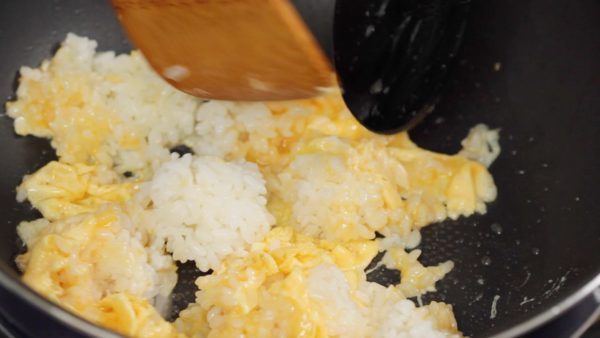 Tenez une spatule dans chaque main et séparez les grumeaux de riz en les recouvrant uniformément avec l’œuf. Continuez de séparer chaque grain de riz mais veillez à ne pas les casser. 