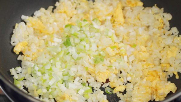 当每粒米饭都炒分散开以后，加入葱段翻炒。