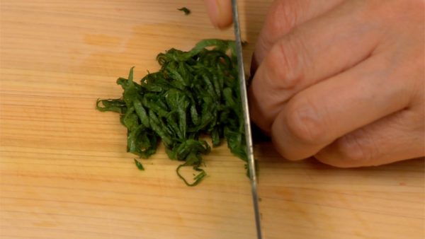 Let's prepare the toppings. Remove the stems of the shiso leaves and roll them together. Cut the roll in half, line them up and thinly shred the shiso.