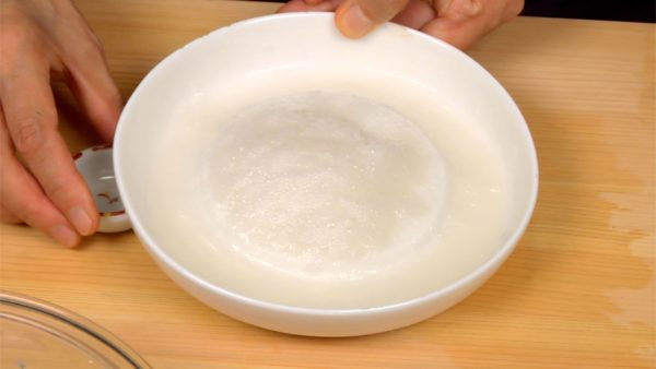 Place the daikon perpendicular to a ceramic grater and grate it in a circular motion. This will help make the grated daikon smooth and delicious. Gather the daikon toward the center and tilt the grater to drain the excess liquid.