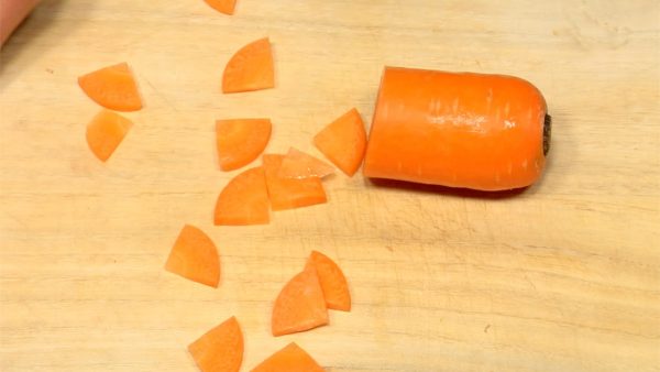 Make a cross-shaped cut on the carrot. Be careful not to cut your hands. Thinly slice the carrot into quarter moons.