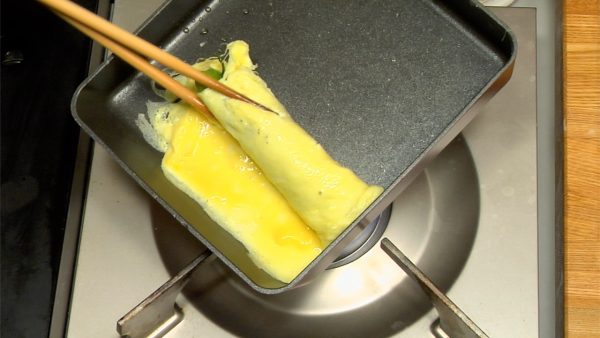 用筷子捲起煮好的雞蛋片，並將其放在切菜板上。