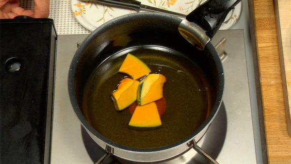 Let's fry the pumpkin and chicken. Place the pumpkin in oiled frying pan and turn on the burner.
