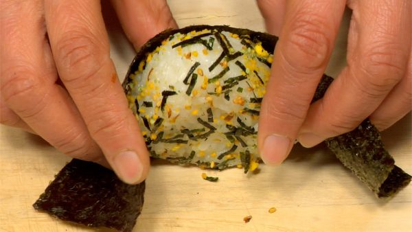 Wrap the onigiri with a sheet of toasted nori. Place it on the bento box divider.