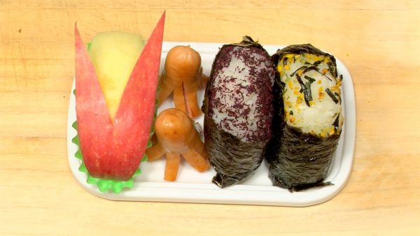 Place the Yukari onigiri, rabbit-shaped apple and octopus-shaped sausage on the bento box divider.