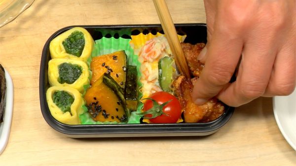 Let's pack the bento box with all the ingredients. Arrange the spinach tamagoyaki, honey glazed pumpkin, potato salad, cherry tomato and karaage fried chicken.