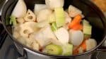 キッチンペーパーで鶏から出た脂を吸い取ります。オリーブオイルを足し火をつけます。熱くなった鍋に人参、たまねぎ、れんこん、里芋、かぶ、セロリを入れます。野菜を軽く炒めます。